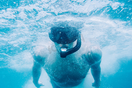 运动男子自由潜水员在水下表面游泳。