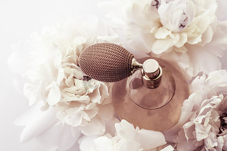 复古香水瓶作为牡丹花背景下的奢侈香水产品、香水广告和美容品牌