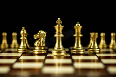 商业黑色摄影照片_棋盘上的金棋子，商业战略概念