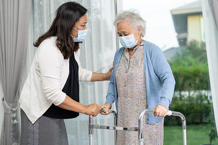 帮助和护理亚洲老年或老年老妇妇女在医院行走时使用健康状况良好的助行器。