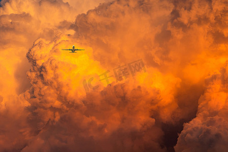 飞机飞过戏剧性的橙色天空和云彩抽象背景
