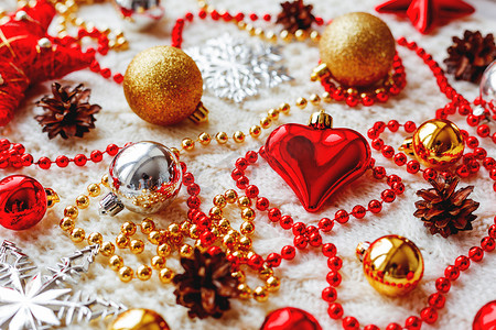金色雪花图案摄影照片_圣诞节和新年背景与装饰-球、星星、银色闪闪发光的雪花、带有装饰图案的针织面料上的心。