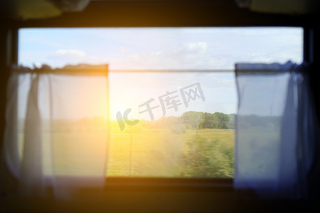 火车自然景观摄影照片_阳光明媚的火车，让旅客在假期期间旅行，在窗户上欣赏自然景观