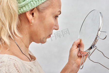 一位老年妇女在化妆前照镜子