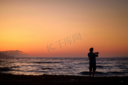 沙滩上用手机拍照的男人