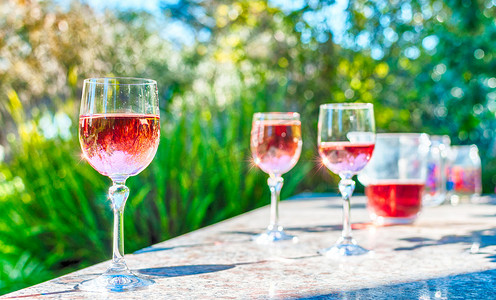 花园桌子上的高脚杯中的桃红葡萄酒