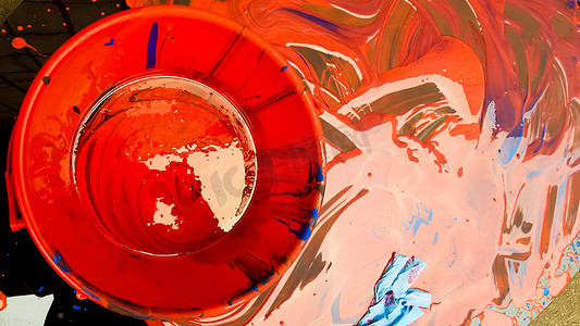 溢出的红色油漆的抽象背景与黑色背景上的桶。