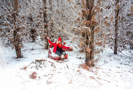 胡闹摄影照片_冬天，女人坐在雪覆盖的松树林里的沙发上