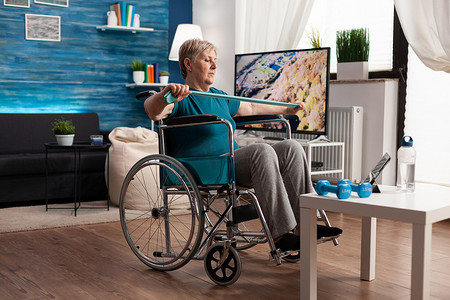 坐轮椅的养老金领取者妇女使用阻力弹力带训练手臂肌肉