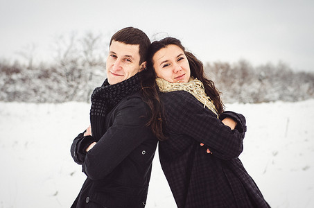 冬天总结摄影照片_一个男孩和一个女孩穿着温暖的衣服和围巾在雪天散步