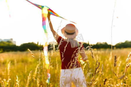 夏天日落时分，快乐的年轻女子在林间空地放着风筝奔跑