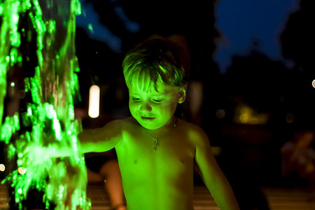 高兴摄影照片_孩子在公园的喷泉里嬉戏，他很高兴。