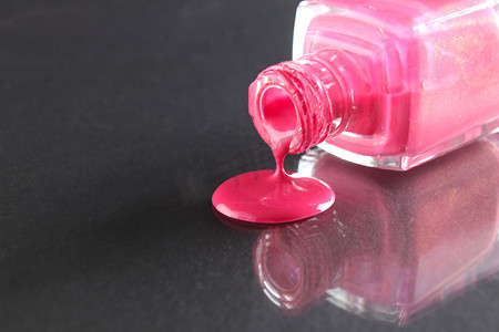 粉色指甲油从黑色背景的瓶中倒出，并有文本复制空间