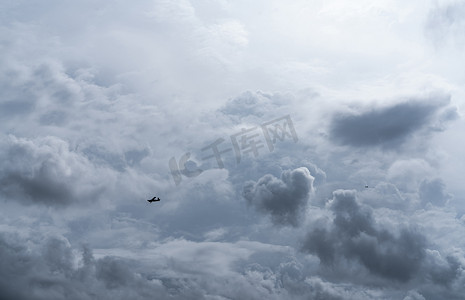 人工播种摄影照片_在多云的天空中造雨的小飞机。