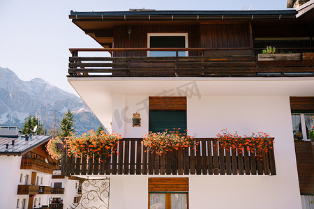 木质花盆摄影照片_位于意大利北部多洛米蒂山脉科尔蒂纳安佩佐镇冬季滑雪胜地的一栋带有木质元素的白色白色房屋。