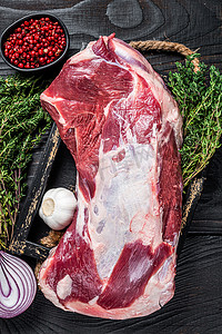 蒸羊腿摄影照片_新鲜生羊肉羊肩肉放在木托盘里，配百里香。