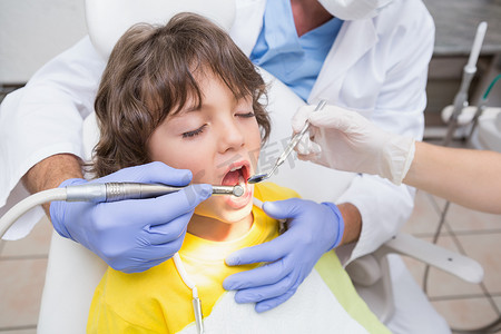 儿科牙医在牙医椅上检查小男孩的牙齿