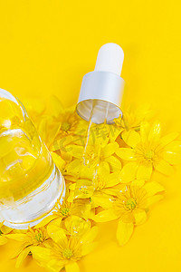 黄色背景上装有移液管血清的瓶子，周围环绕着春花