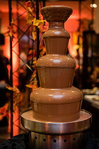巧克力喷泉摄影照片_有层数和温暖的彩色背景的巧克力喷泉