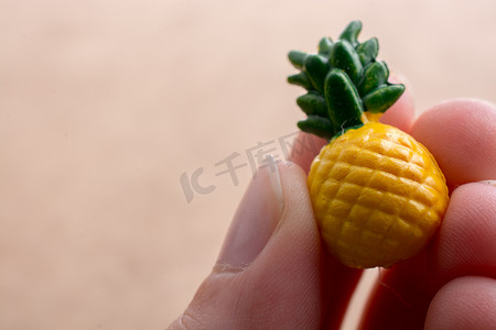 绿色食物插图摄影照片_手拿着背景上的小菠萝模型