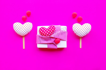 粉红色背景上装有情人节爱心的礼品盒。