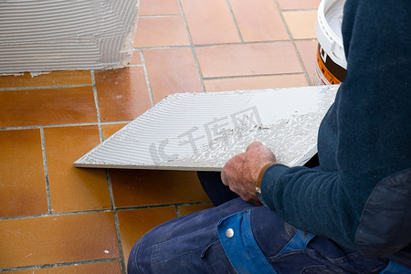 瓷砖工在铺设瓷砖之前先在瓷砖上涂上胶水