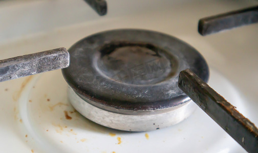 油污的厨房摄影照片_厨房里的脏煤气灶，用于烹饪，表面有植物油污和烧焦的食物残渣，特写。