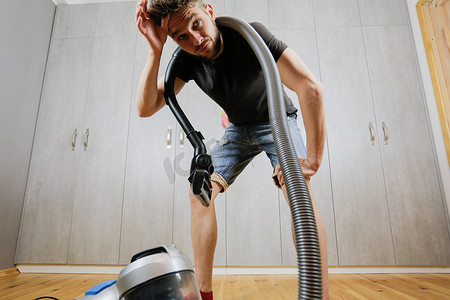 一个有吸尘器的男人厌倦了打扫房子