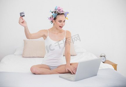 用电脑在网上购物的卷发器中惊艳的天然棕发女性