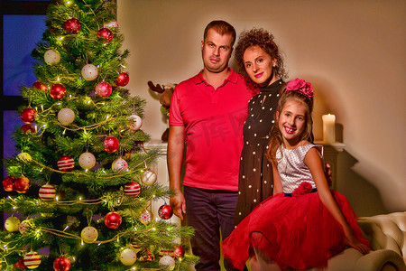 有孩子的家摄影照片_圣诞树附近有孩子的幸福大家庭。