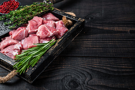 丁肉摄影照片_生切丁的猪肉幼崽肉与香料放在质朴的托盘中。