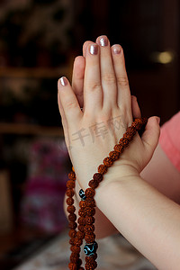 女人手拿着金刚菩提念珠和合十手印。