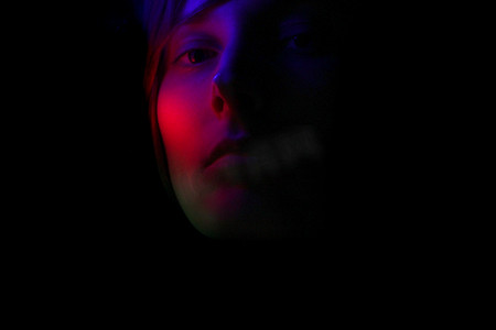 一个女孩在彩色灯光下的黑暗肖像