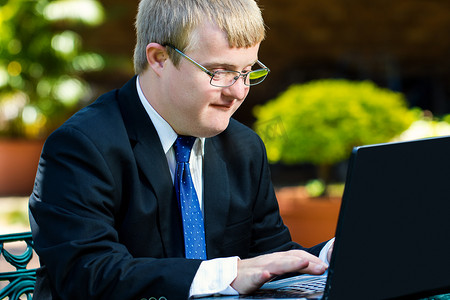 在膝上型计算机上工作的年轻有残障的商人。