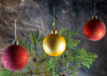 圣诞树木摄影照片_冷杉树枝背景上的金色和红色圣诞球。