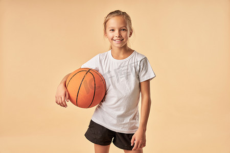 拿着比赛球的快乐的女孩篮球运动员