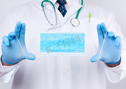 一件白色外套的医生，蓝色乳汁无菌手套拿着纺织品