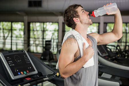 在健身房跑步机上喝水的人