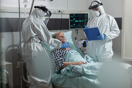 身穿个人防护服的医务人员用氧气面罩帮助患者呼吸