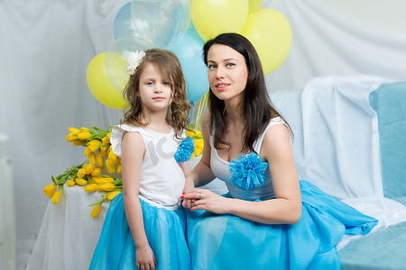 妈妈和女儿坐在沙发上，手里拿着一束鲜花。