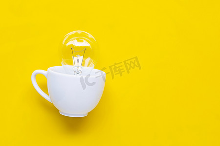 电商渐变背景摄影照片_在黄色背景上的白色杯子里的灯泡。