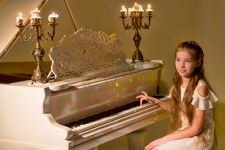 小女孩在烛光下弹钢琴。