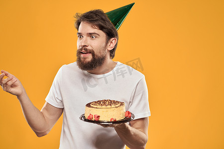 英文版生日快乐摄影照片_一个留着胡子、戴着蛋糕、戴着帽子庆祝生日的男人