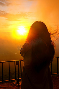 一个女人站着看雾和日出的影子。