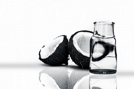 一起喝果汁摄影照片_生有机切干椰子连同水一起放在一个透明玻璃瓶中，用白色隔开，并带有反射。