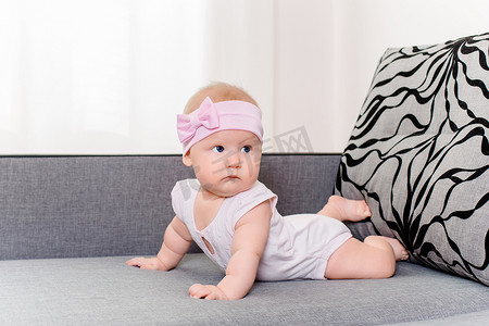 线上头图摄影照片_沙发上头上戴着绷带和蝴蝶结的女婴的肖像