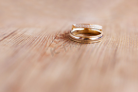一对金色结婚戒指，在破旧的木制背景上镶有钻石。