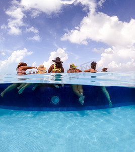 年轻女性在加勒比海酒店泳池中玩耍的半水下分裂图像。