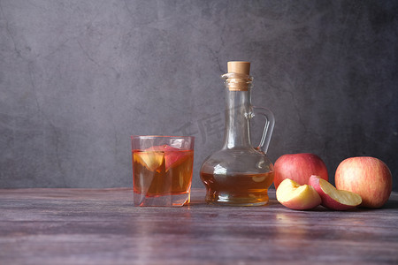 玻璃瓶中的苹果醋，桌上有新鲜的青苹果
