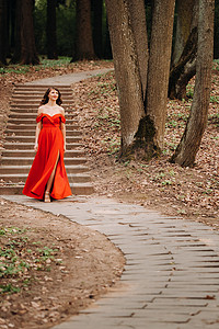 一个穿着长发红裙、长发在树林公园散步的笑女孩的春天肖像